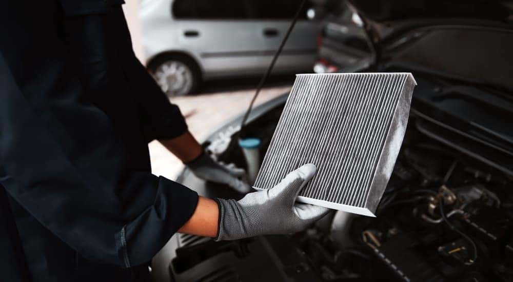 A mechanic is shown replacing a car's air filter.