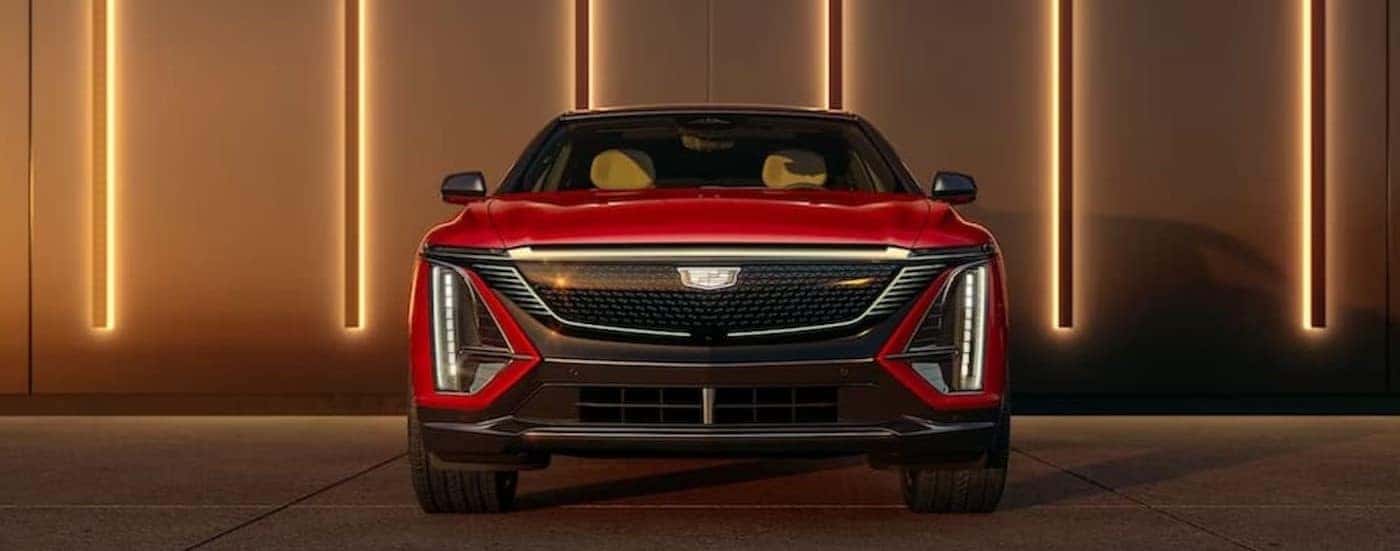 A red 2024 Cadillac LYRIQ is shown parked near several lights on a wall.