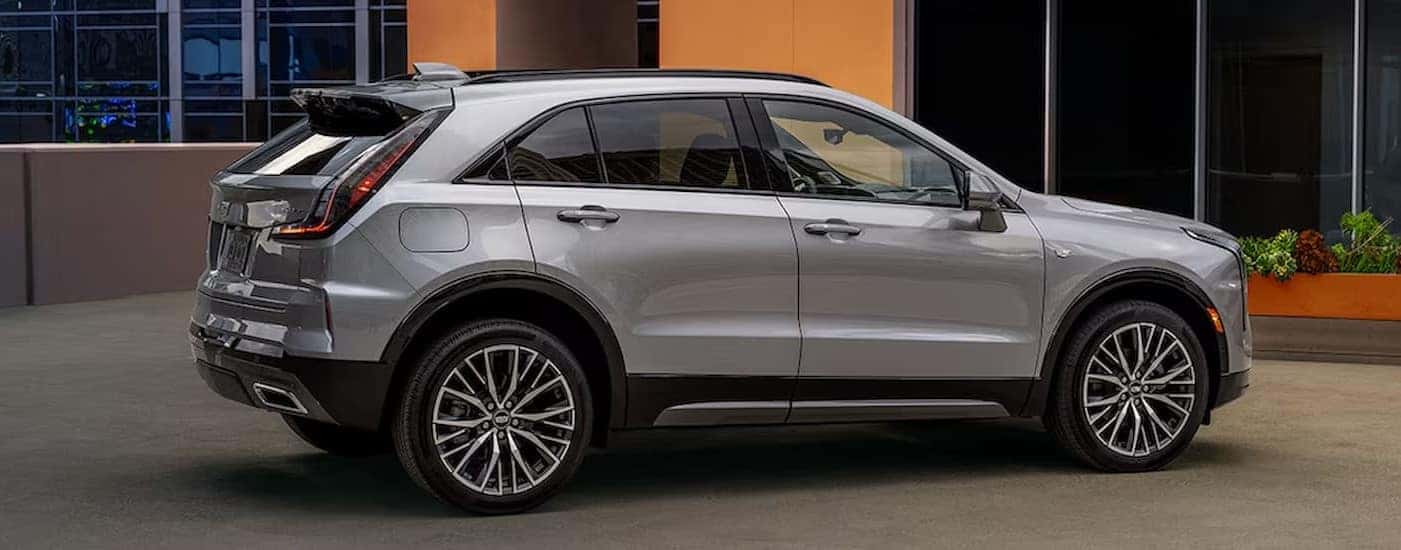 A silver 2024 Cadillac XT4 is shown parked near a yellow building.