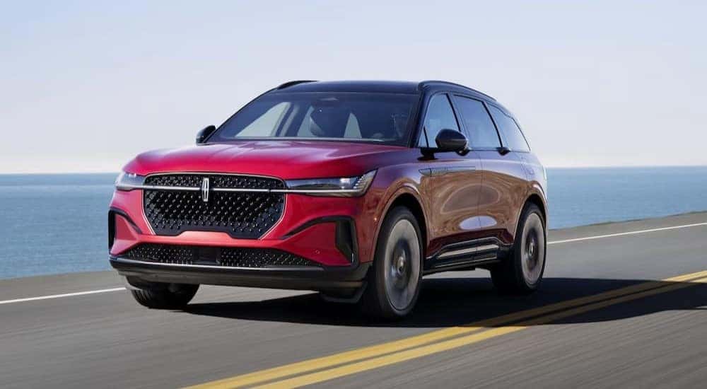 A red 2024 Lincoln Nautilus is shown driving on a highway.