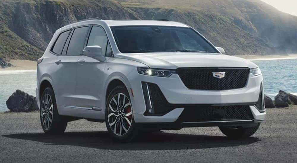 A white 2024 Cadillac XT6 for sale is shown parked near an ocean.