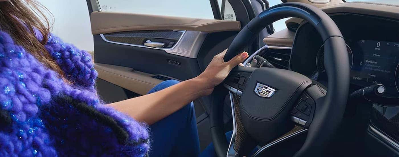 A person is shown gripping the steering wheel in a 2024 Cadillac XT6.