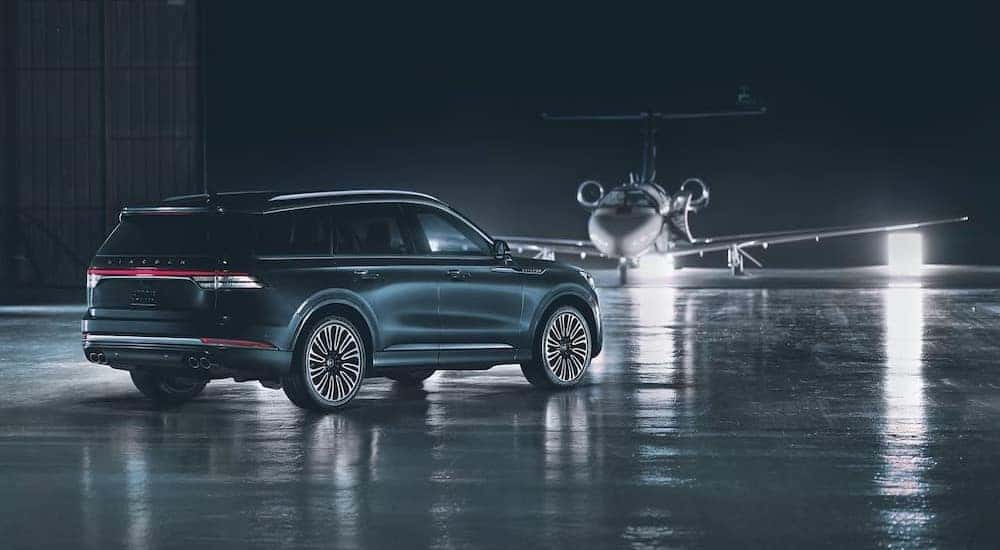 A black 2024 Lincoln Aviator is shown parked in a hangar near an airplane.