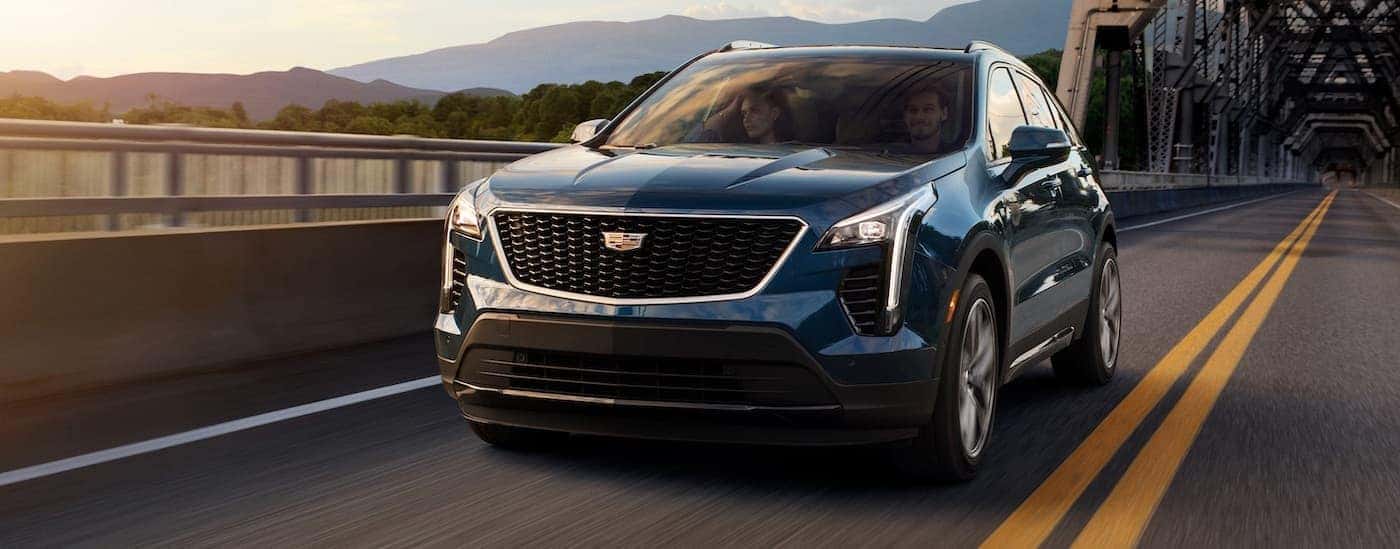 A blue 2020 Cadillac XT4 is shown driving to visit a used Cadillac dealer.