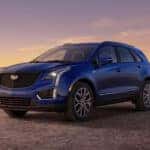 A blue 2025 Cadillac XT5 parked in the desert at sunset.