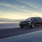 A black 2025 Cadillac CT4 driving down a road.