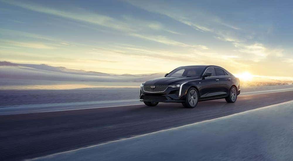 A black 2025 Cadillac CT4 driving down a road.