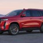 A red 2024 Cadillac Escalade ESV is shown parked off-road.