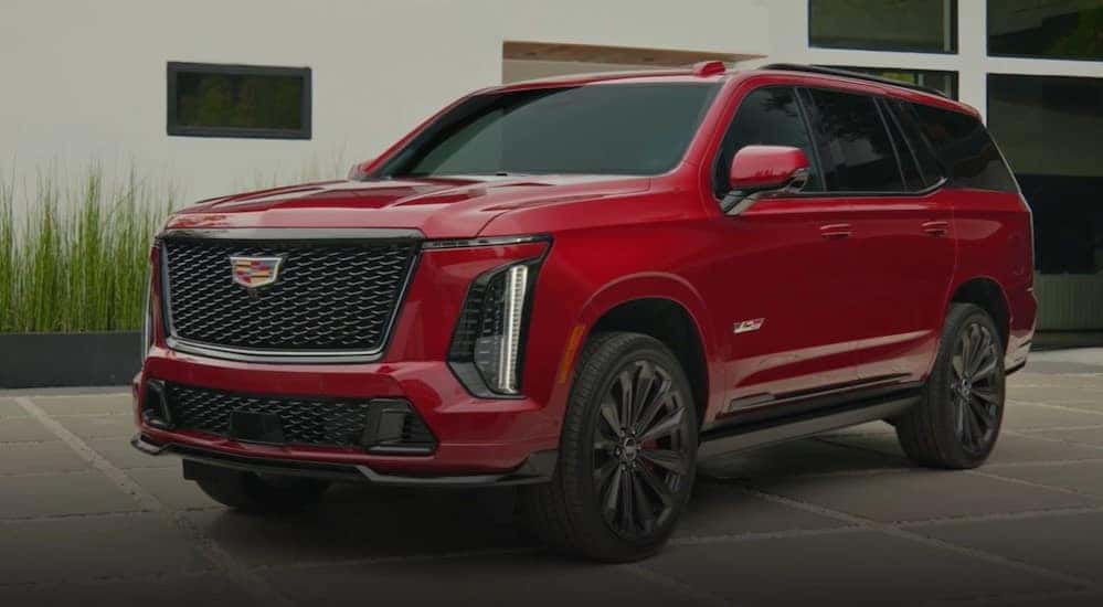 A red 2025 Cadillac Escalade-V is shown parked on a driveway.