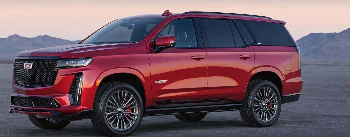 A red 2025 Cadillac Escalade-V is shown parked off-road.