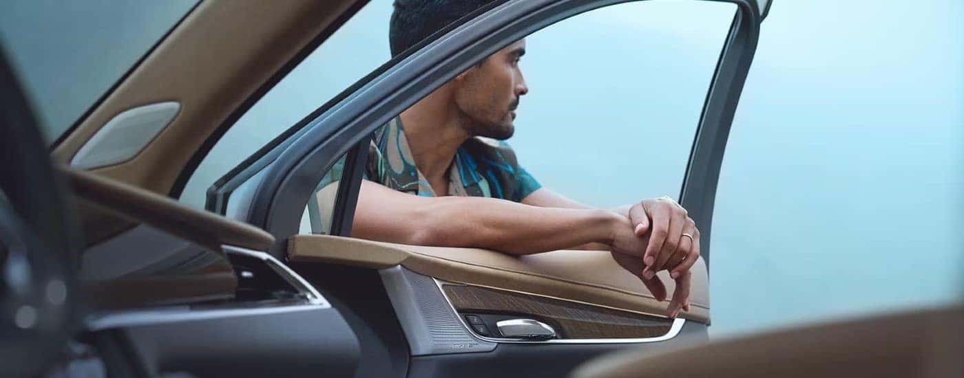 A person is shown leaning against a 2025 Cadillac XT6.