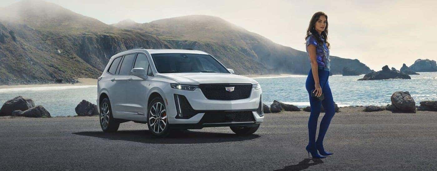 A white 2025 Cadillac XT6 is shown parked near an ocean.