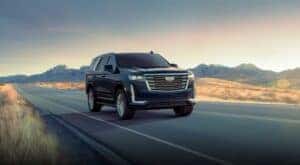 A black 2024 Cadillac Escalade for sale in Atlanta driving down a road.