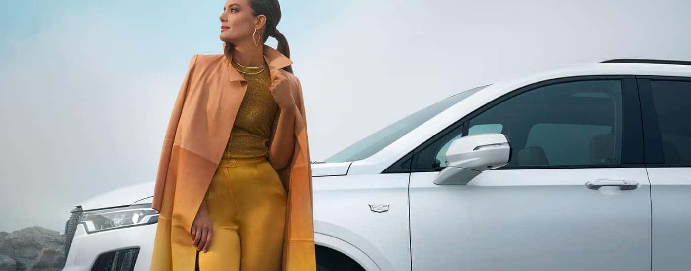 A person leaning against a white 2025 Cadillac XT6 for sale in Atlanta.