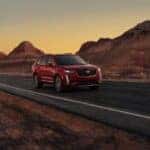 A red 2025 Cadillac XT6 for sale in Atlanta driving on a highway.