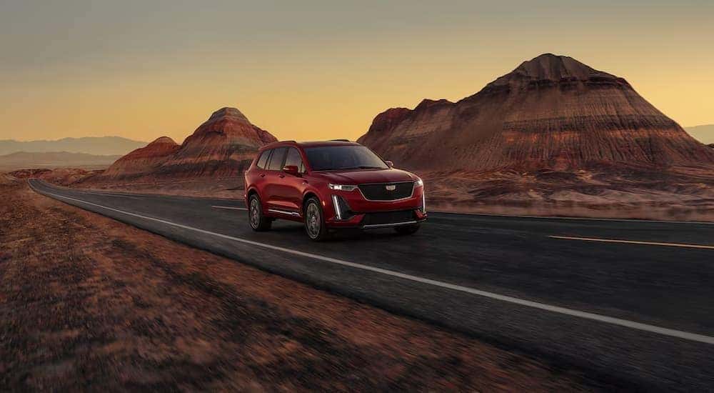 A red 2025 Cadillac XT6 for sale in Atlanta driving on a highway.