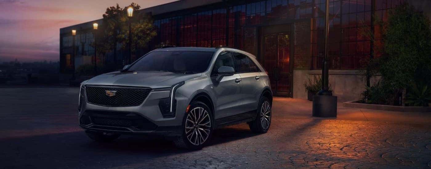 A grey 2024 Cadillac XT4 is shown parked by a building.
