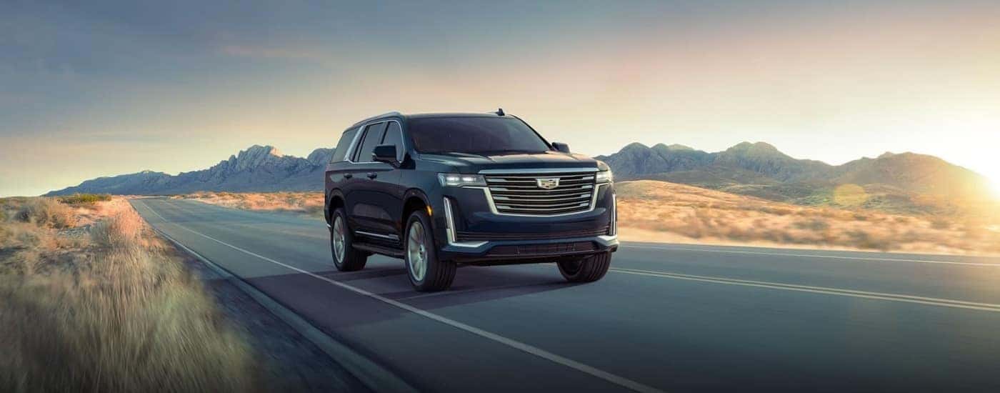 A black 2024 Cadillac Escalade for sale in Atlanta driving down a road.