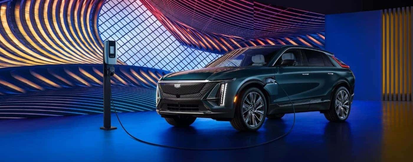 A teal 2024 Cadillac LYRIQ charging under neon lights.