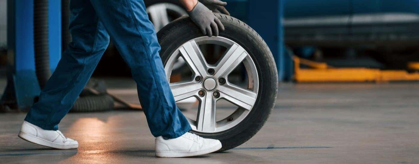 A mechanic rolling a tire in a service center.