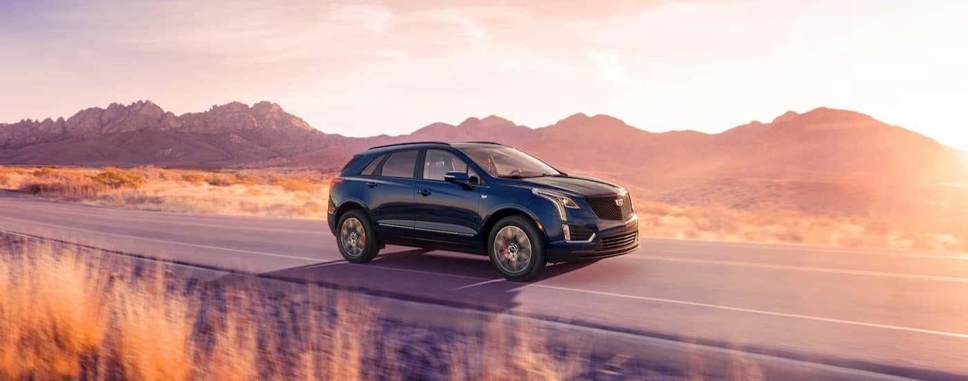 A blue 2025 Cadillac XT5 driving on a highway.