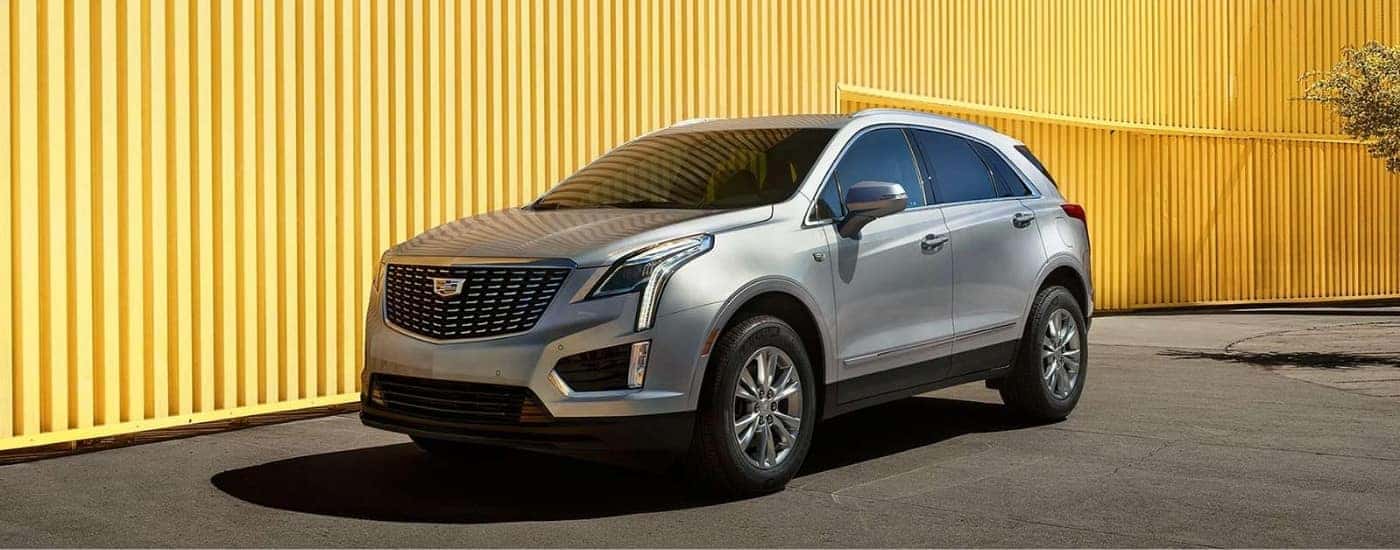 A silver 2020 Cadillac XT5 is shown parked near a large yellow wall.
