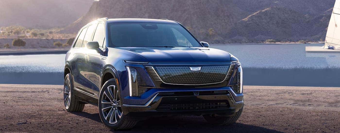 A blue 2025 Cadillac VISTIQ parked near a lake
