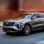 A silver 2025 Cadillac XT4 driving down a city street