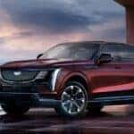 A red 2026 Cadillac Escalade IQ parked outside of a city.