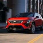 A red 2026 Cadillac OPTIQ driving in a city.