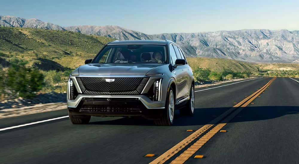 Silver 2026 Cadillac VISTIQ driving along a mountainous roud