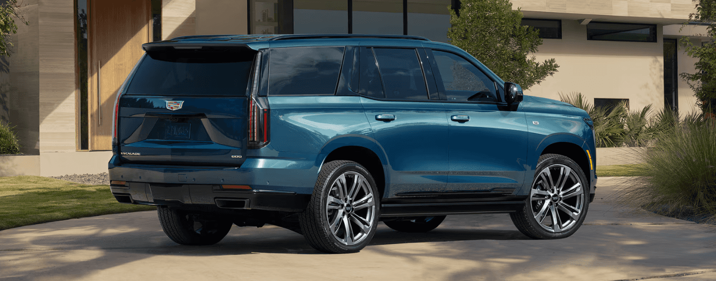 A blue 2026 Cadillac Escalade shown parked in front of a house.