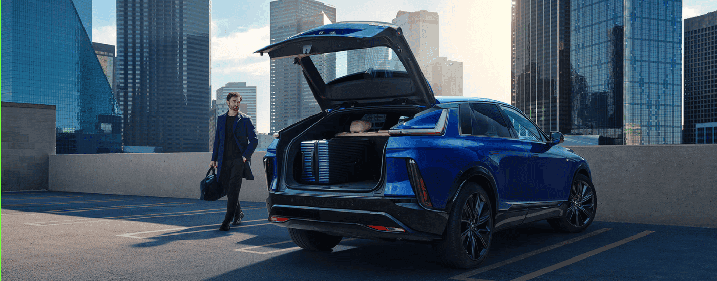 A person putting their belongings into the trunk of their blue 2026 Cadillac Lyriq