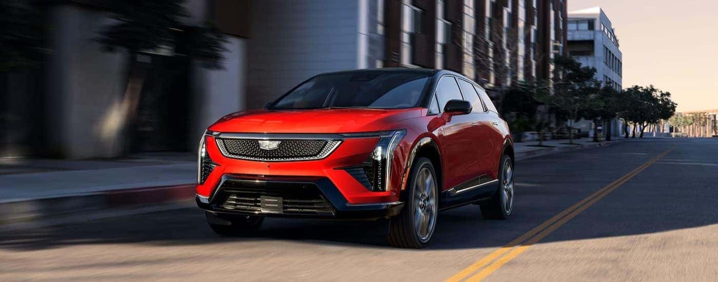 A red 2026 Cadillac OPTIQ driving in a city.