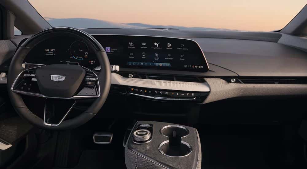 The front interior of a 2026 Cadillac OPTIQ showing the steering wheel and infotainment display.