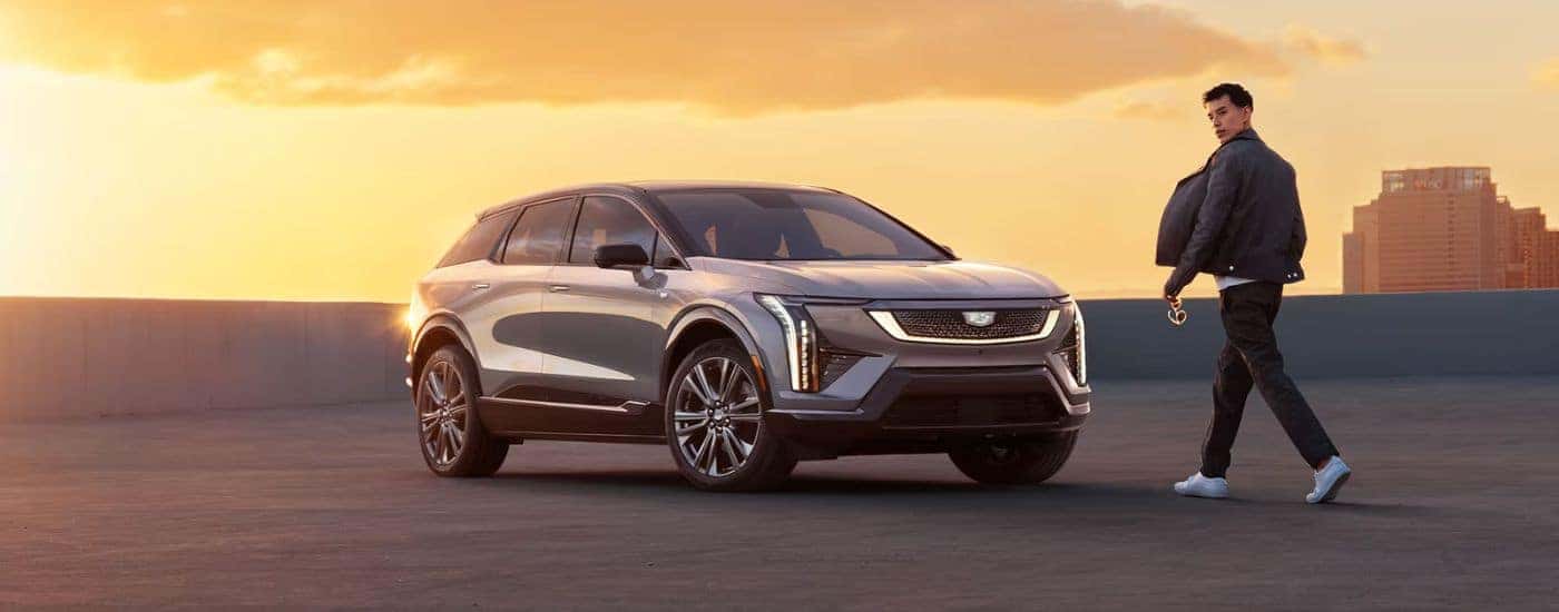 A silver 2027 Cadillac OPTIQ parked on a rooftop by a man.