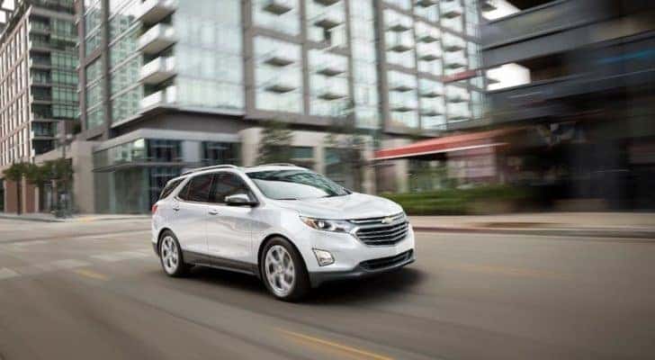 A white 2020 Chevy Equinox is shown driving on a city street.