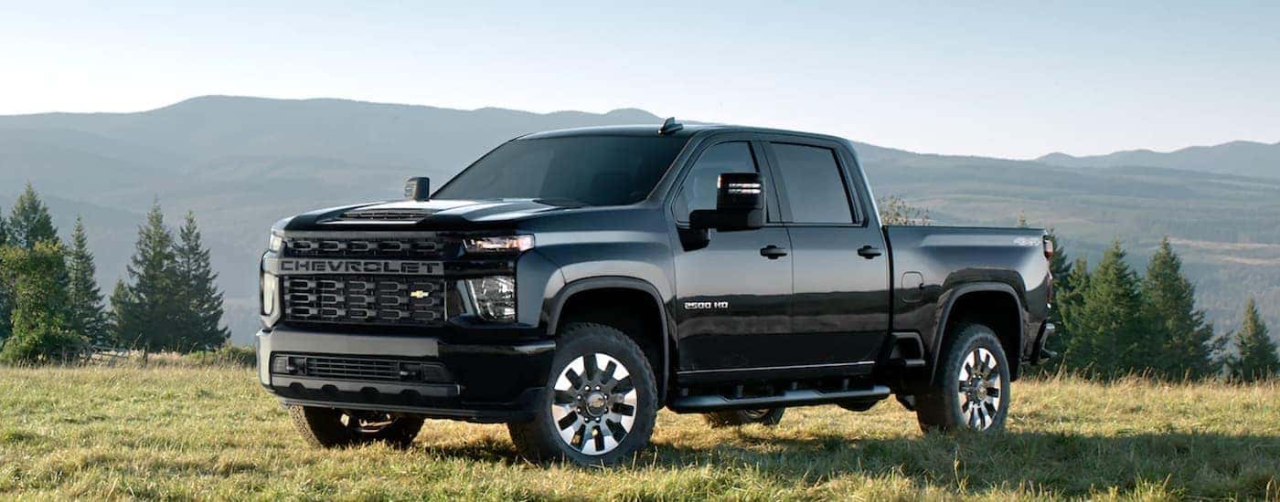 A black 2023 Chevy Silverado 2500 HD is shown from the side parked in a field.