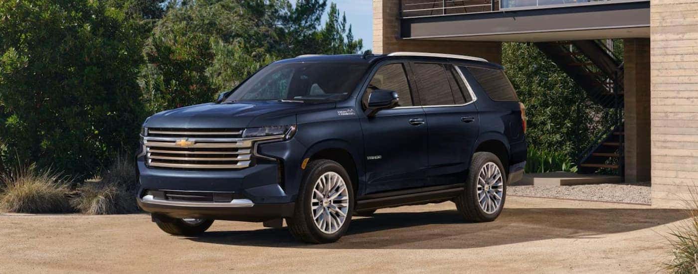 A blue 2023 Chevy Tahoe is shown parked in front of a house.