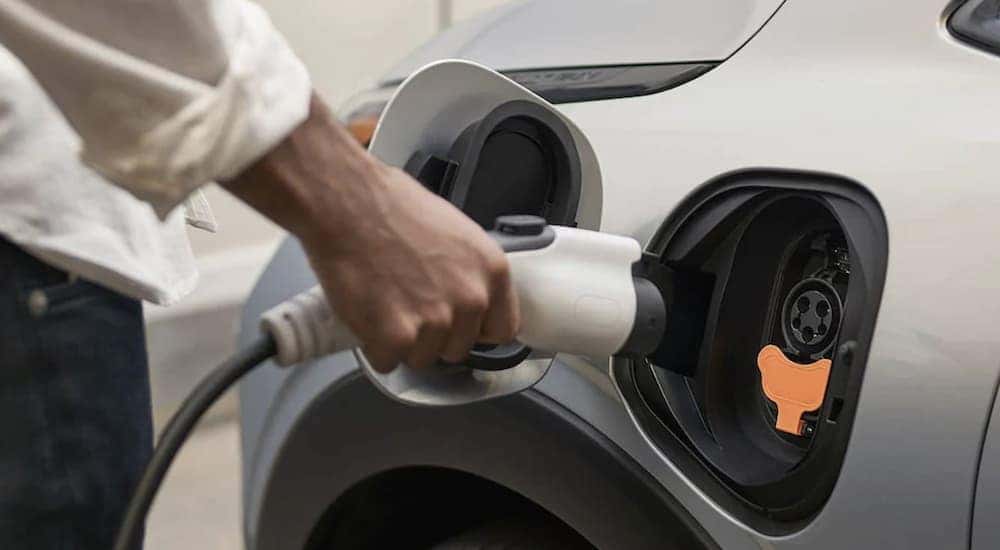 A person is shown plugging a charge cable into a silver 2023 Chevy Bolt EUV.