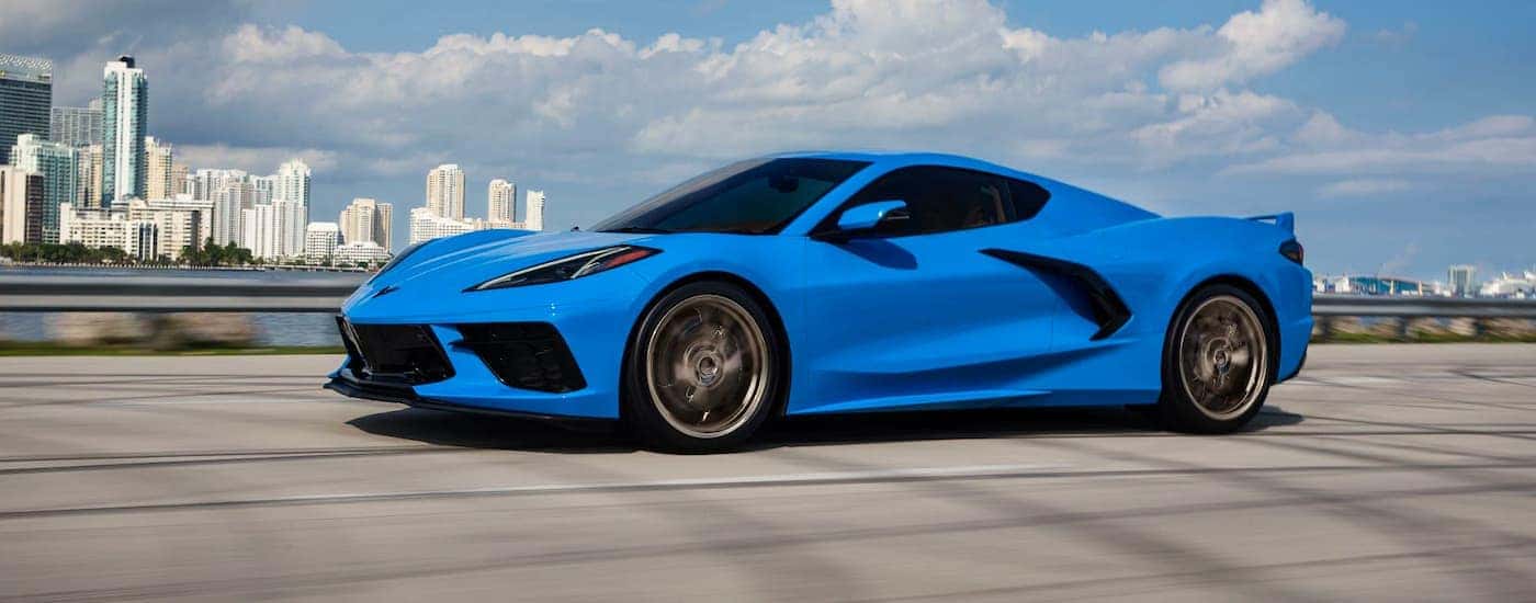A blue 2023 Chevy Corvette 3LT is shown driving past a city after leaving a Chevy dealer near Duluth…