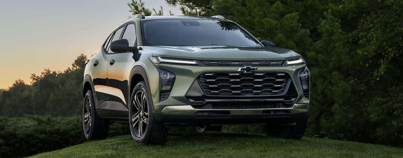 A green 2024 Chevy Trax is shown parked on a grassy hill.