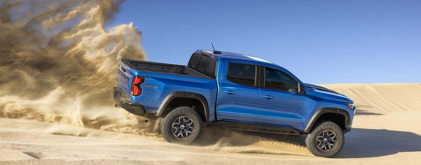 A blue 2023 Chevy Colorado ZR2 is shown from the side on a sand dune after leaving a dealer that has…