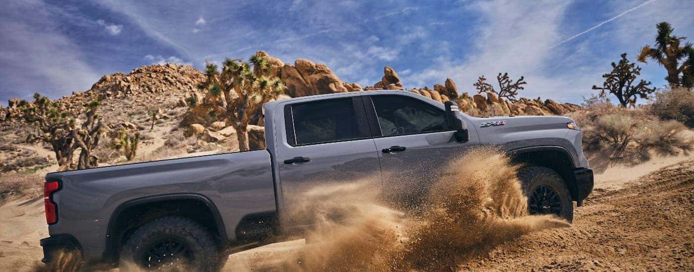 A grey 2024 Chevy Silverado 2500 HD ZR2 is shown from the side off-roading on a desert road.