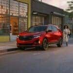 A red 2024 Chevy Equinox RS is shown parked near a Chevy Equinox dealer.