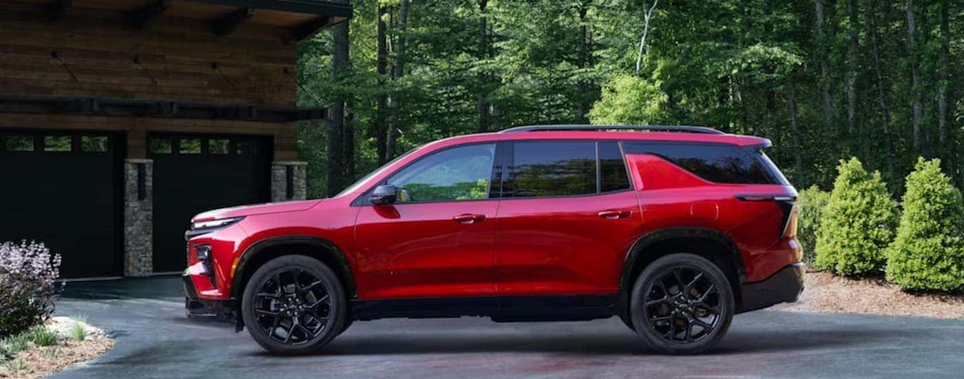 A red 2024 Chevy Traverse is shown from the side parked in a driveway.