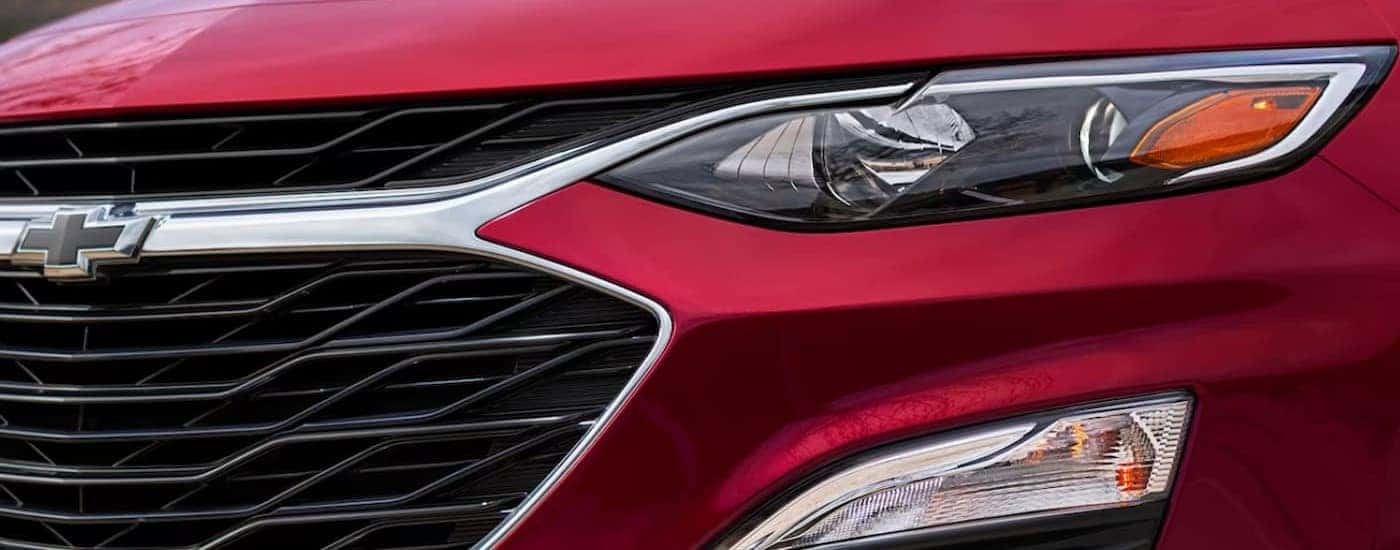 A close-up of the front end on a red 2024 Chevy Malibu is shown.