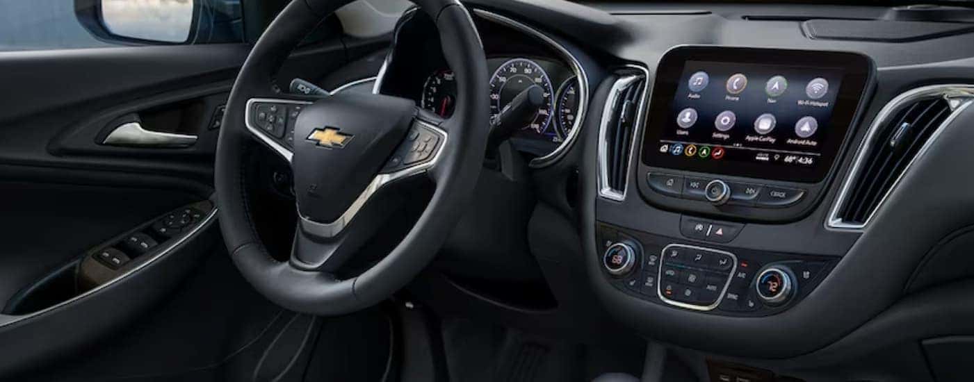 The black interior and dash of a 2024 Chevy Malibu is shown.