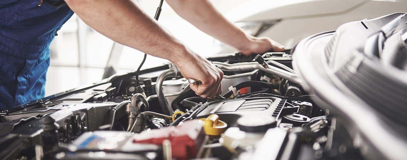 A mechanic is shown working on an engine.