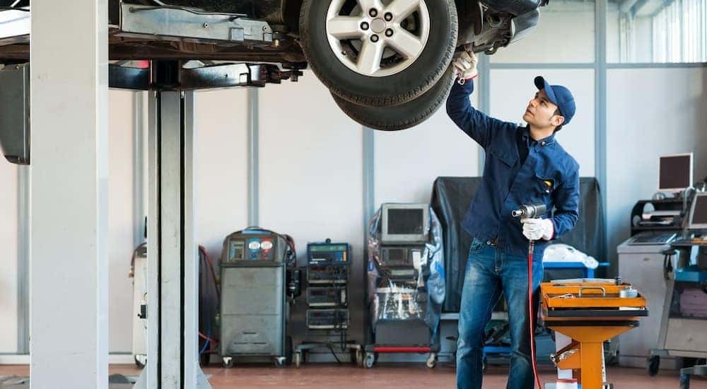 A mechanic is shown working under a vehicle.